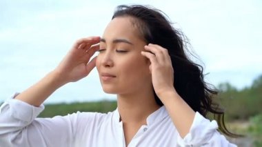 Güzel Asyalı bir kadının portresi. O, saçlarını dokunmadan ve gülümseyerek bir kenara bakıyor.