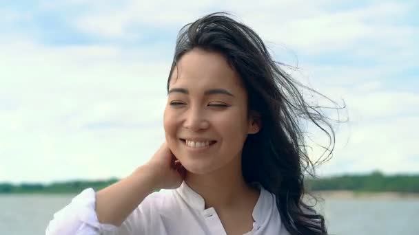 屋外でかわいい若いアジアの女性の肖像画 脇を見て 彼女の髪に触れて微笑んでいた ハンドヘルドショット — ストック動画