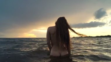 Uzun saçlı, çekici genç kadın denizde durup poz lar. Arkadan görüntüle. 