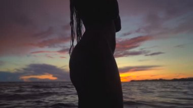 Gün batımı gökyüzünün üzerindeki kadın siluetinin görüntülerini kapatın. Slowmotion.