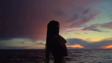 Denizde genç bir kadın. Yağmurlu hava, gün batımı. Slowmotion.