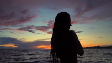 Deniz ve gün batımı gökyüzü üzerinde kadının siluet portre. Slowmotion.