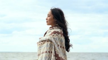 Mutlu, gülümseyen Genç Asyalı kadın açık havada portresi. Deniz kıyısına yakın ayakta, ekose giymiş. Gülümsüyor, manzarayı eğlendiriyorum. Kenara görünüm.