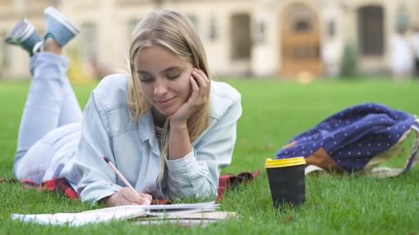 Studentessa Sdraiata Sull Erba Che Scrive Nel Quaderno Sorridente Emozioni — Video Stock