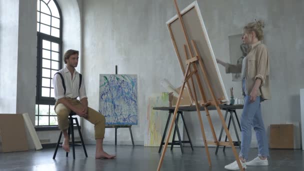 スタジオで男性の肖像画を描くアーティスト女性 — ストック動画