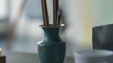 Resimle çalışan kadın ressam. Araçlarla masaya odaklanın ve sonra sanat kadını ve resimde.