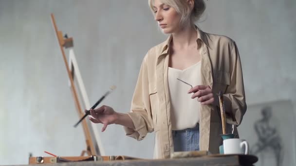 テーブルの上に絵画道具を選ぶ女性画家 スローモーション — ストック動画