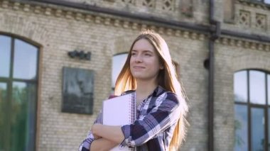 Öğrenci kız üniversite binasının yanında duran ve güzel, sakin bir gün zevk. Olumlu duygular. Slowmotion. el çekimi.