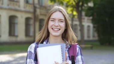 Genç kadının açık havada portresi. Şaka, gülümseme ve kameraya bakmak.