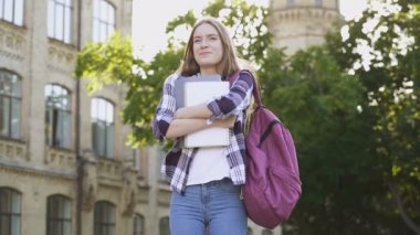 Üniversitenin yanında duran öğrenci kız. Mutlu, pozitif, duyguları sevin. El yapımı atış. Slowmotion.