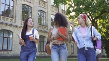 Kız arkadaşlar dışarıda yürüyorlar, birbirleriyle konuşuyorlar, gülümsüyorlar ve gülüyorlar. El çekimi.