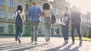 Kampüs binasının yanındaki parkta yürüyen arkadaşlar. Arkadan bak. El çekimi.