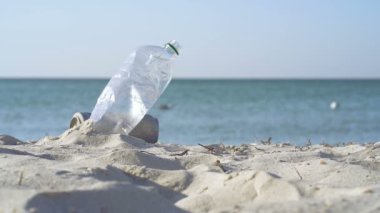 Deniz kenarındaki kumda plastik şişe. Slowmotion. Ekoloji kavramı.