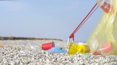 Adam çöp çöp kullanarak, deniz plajında plastik ve diğer çöp almak. Slowmotion.