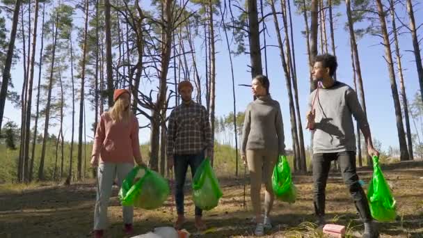 志愿者们拿着塑料袋在森林里行走 蚂蚁垃圾棒 讨论塑料问题 关注志愿者 在地面与垃圾 慢动作 — 图库视频影像