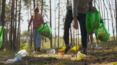 Bir grup gönüllü ormanda çöp ve plastik topluyor. Kirlilik kavramı. Slowmotion.