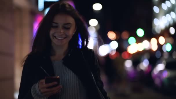 Jovem Mulher Atraente Andando Cidade Noturna Com Smartphone Nas Mãos — Vídeo de Stock