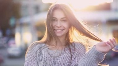 Mutlu, gülümseyen ve neşeli genç bir kadının portresi. Sokakta dikilip kameraya bakmak. Yavaş çekim.