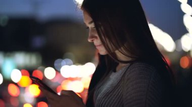 Akıllı telefon tutan mutlu genç bir kadının portresi. Gece vakti..