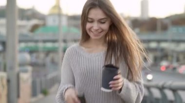 Gülümseyen, mutlu, uzun saçlı kadın sokakta yürüyor. Olumlu, neşeli duygular. El kamerasıyla..