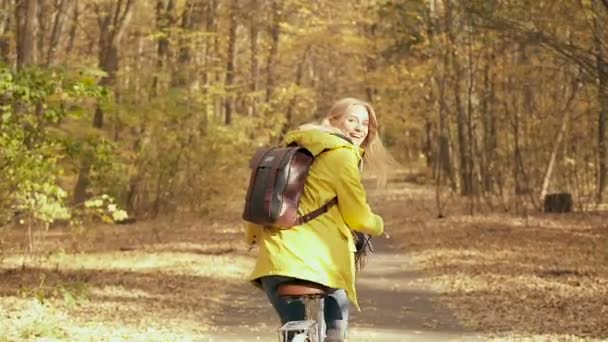 手持拍摄的年轻金发女子享受生活和骑自行车在森林里 秋天的季节 慢动作 — 图库视频影像