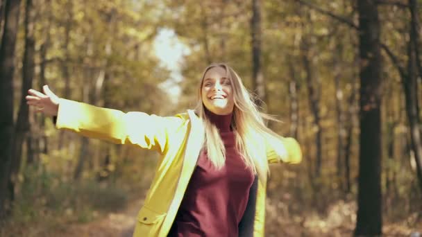 在秋天的公园里 一个快乐的金发女人在自己身边打转 慢动作 — 图库视频影像