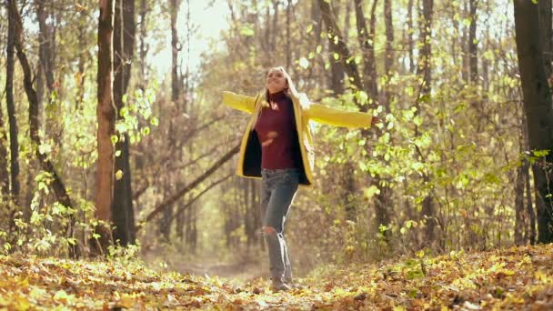 快乐的金发女人在秋天的森林里打转 树叶从树上掉了下来 慢动作 — 图库视频影像