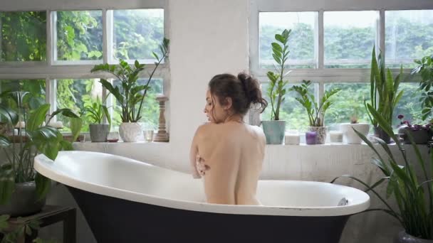 迷人的黑发女人坐在浴缸里看着摄像机 慢动作 — 图库视频影像