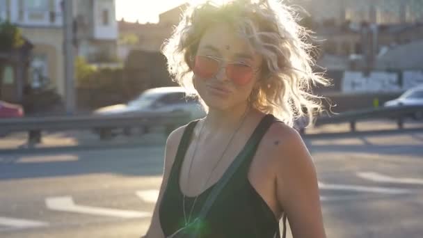 通りにポーズをとってサングラスをかけた幸せそうな前向きな女性 スローモーション — ストック動画