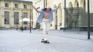 Genç bir kadın eğleniyor ve kaykaya biniyor. Yavaş çekim.