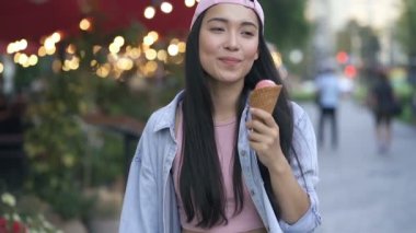 Sokakta dondurma yiyen Asyalı genç bir kadın. Yavaş çekim.