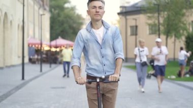Elektrikli scooter kullanan yetişkin bir adam. Yavaş çekim.