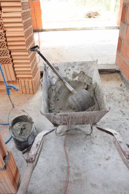 Tuğla döşemeye hazır metal bir el arabasının harç çimentosu.