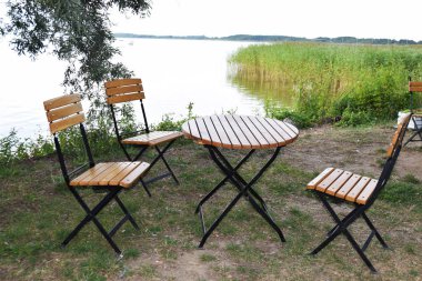 boş ahşap masa ve göl kenarındaki ahşap sandalye