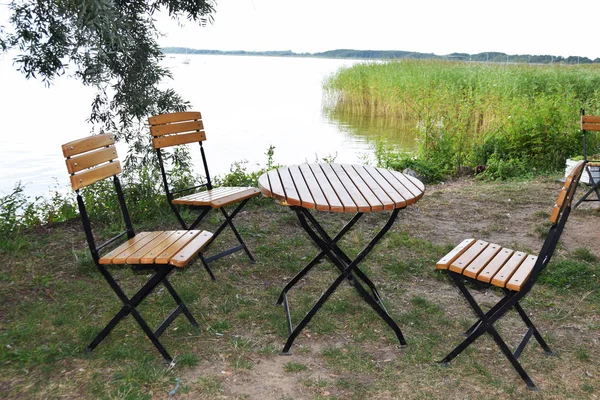 boş ahşap masa ve göl kenarındaki ahşap sandalye