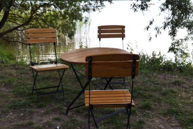 boş ahşap masa ve göl kenarındaki ahşap sandalye