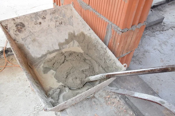 Tuğla döşemeye hazır metal bir el arabasının harç çimentosu.