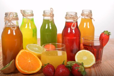 bir cam şişe farklı taze meyve suları tam eşliğinde turuncu ve çilek suyu
