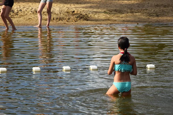 Chica en un traje de baño sale del lago — Foto de Stock