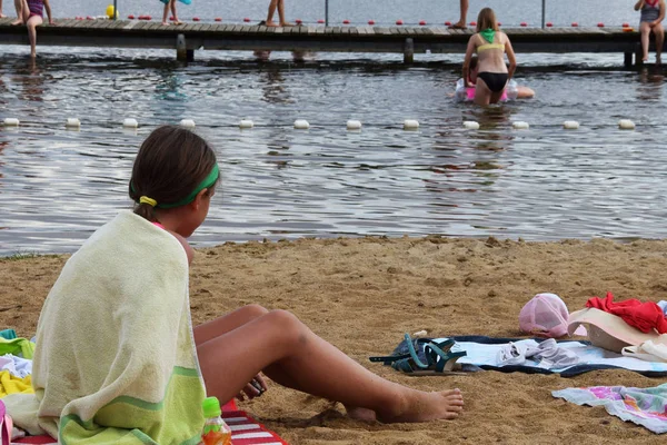 Chica envuelta en una toalla sentada en la playa — Foto de Stock