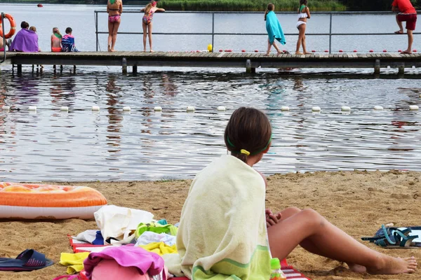 Chica envuelta en una toalla sentada en la playa — Foto de Stock