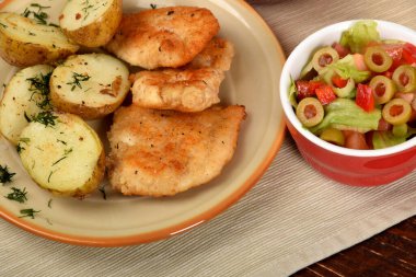 Kızarmış patates ve pirzola yanında domatesli yeşil marul ve yeşil zeytin.