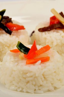 Beyaz tabakta sebzeli üç yığın beyaz pirinç, garnitür olarak.