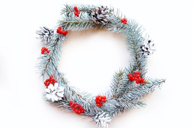 Beyaz arka planda çam kozalaklı Noel çelengi ve yaban mersini. Düz konum, üst görünüm, kopyalama alanı