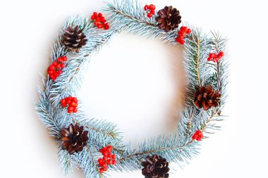 Beyaz arka planda çam kozalaklı Noel çelengi ve yaban mersini. Düz konum, üst görünüm, kopyalama alanı