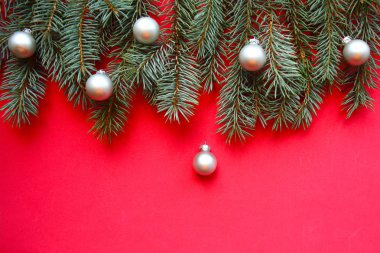 Kırmızı arka planda beyaz takılar olan Noel ağacı dalları. Düz konum, üst görünüm, kopyalama alanı