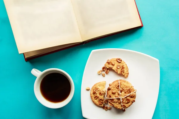 Flat lay photo with coffee cup, open book and cookies on blue background. Flat lay, top view