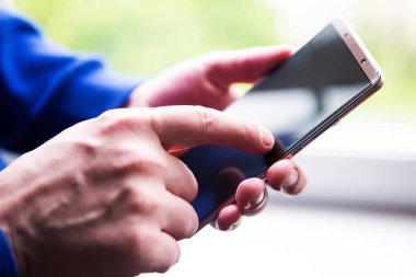 Pencerenin yanında cep telefonu kullanan bir adama yaklaş