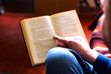 Adam kanepede oturup kitap okuyor.