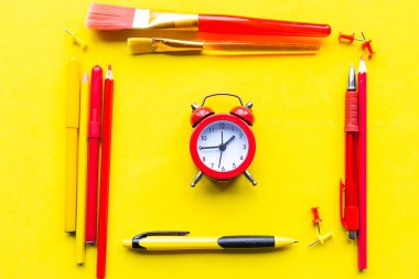 Alarm saati ve parlak sarı arka planda okul malzemeleri. Okul konseptine dönelim.